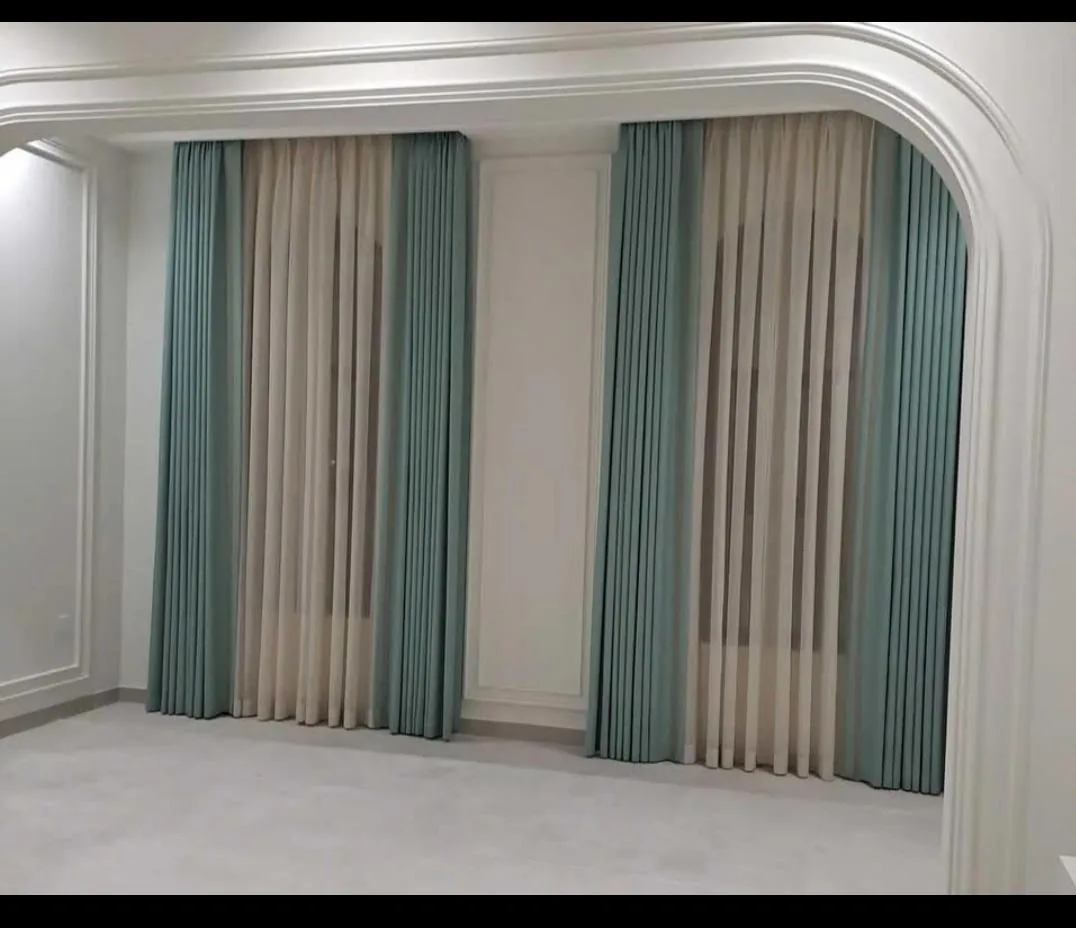 Structured Roman-fold curtains combining tidy lines with soft, layered fabric tones.